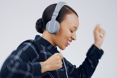 Moving to the music. Studio shot of an attractive young woman dancing against a grey background.の写真素材