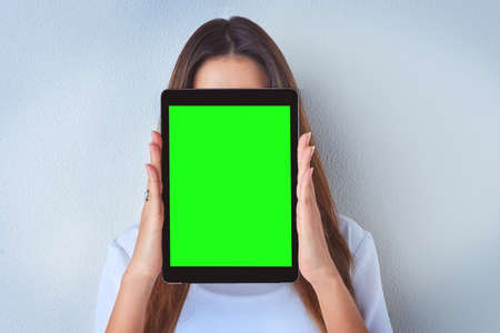 Shes hiding behind her posts online. an unrecognizable woman holding a digital tablet against a blue...