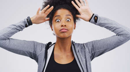 Thats a hair raising story. Studio shot of a young woman making a funny face against a gray...