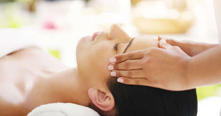 Those are some miracle hands. a young woman getting a head massage at a spa.の写真素材