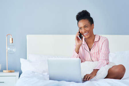 Shes having a productive start to the day. an attractive young woman taking a phone call while using...