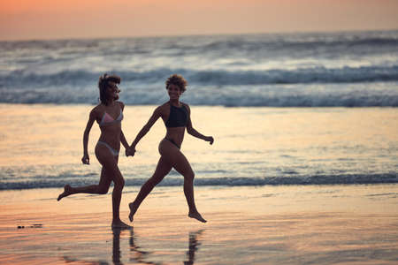 Running off with the one I love most. two young women enjoying themselves at the beach.の写真素材