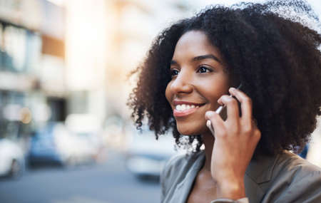 Shes free to talk business at any time. a young businesswoman talking on a cellphone in the city.の写真素材
