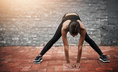 Ill continue stretching towards my goals. a sporty young woman exercising outdoors.の写真素材
