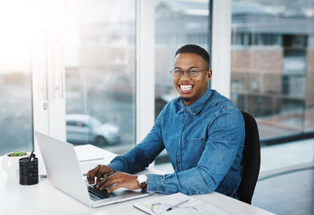 I just love my job, thats it. Portrait of a young businessman working at his desk in a modern...
