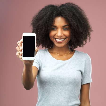 All the APPeal of a mobile app. Studio shot of an attractive young woman holding a smartphone with a...