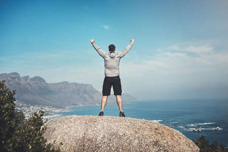 I was born to conquer the world. Rearview shot of a man standing on the top of a mountain.の写真素材