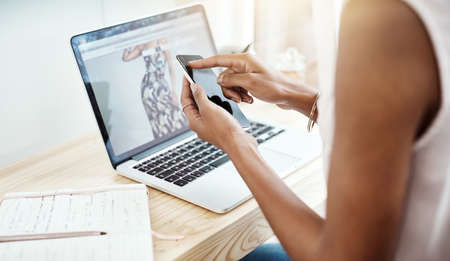 Communication is a key ingredient to success. High angle shot of an unrecognizable young businesswoman reading a text message while working in her home office.の写真素材
