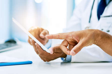 Have a look at this. an unrecognizable doctor and patient looking at test results on a digital tablet inside of a hospital during the day.の写真素材
