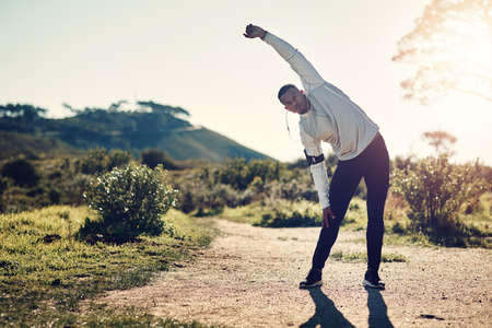 Fresh air and exercise. Full length shot of a handsome young man stretching before exercising outdoors.の写真素材