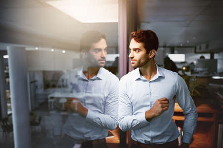 There are so many goals Im still going for. a young businessman standing in an office at night.の写真素材