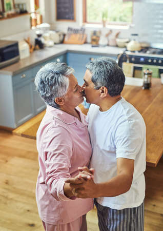 They still have the moves. a carefree elderly couple having a dance while sharing a kiss inside of...