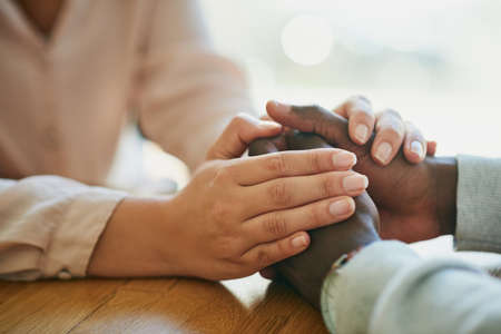 Comfort, kindness and forgiveness with a biracial couple holding hands, united in support in a...