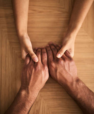 Man and woman holding hands sharing feelings of love, support and trust together on a table. Closeup...