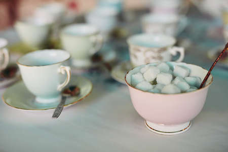 Its all about how many cubes you take with tea. Closeup shot of tea cups laid out on a table at a tea party inside.の写真素材