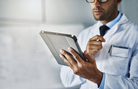 Every expert carries modern tools around. Closeup shot of an unrecognizable doctor working on a digital tablet.の写真素材