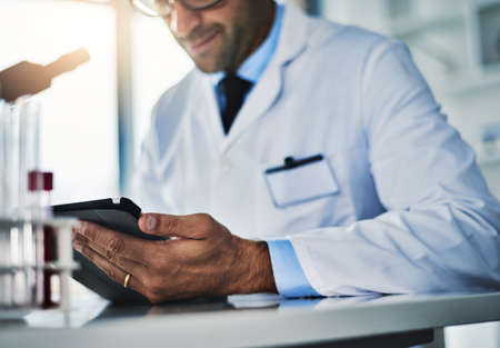 Proving another theory correct yet again. a scientist using a digital tablet while working in a lab.の写真素材