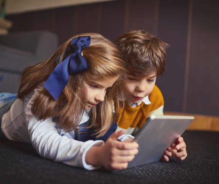 Kid-friendly apps are so popular these days. a little boy and girl using a digital tablet at home.の写真素材