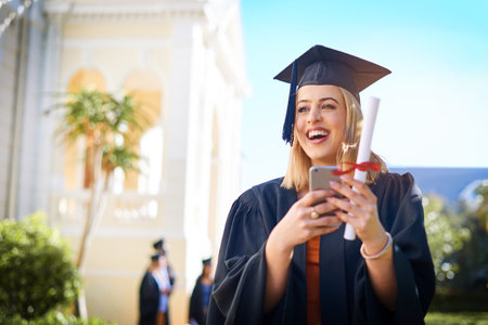 Im getting so many likes for this milestone. a happy young woman standing outside on graduation day.の写真素材