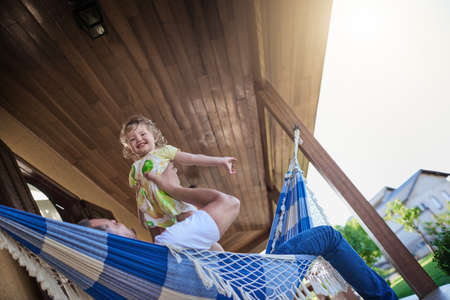 Shell fly high with Daddys love and support. a father and his little daughter bonding together on a hammock outdoors.の写真素材