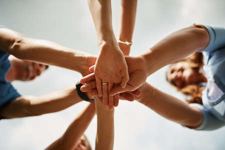 Low angle shot of a family of four standing with their hands in a huddle.