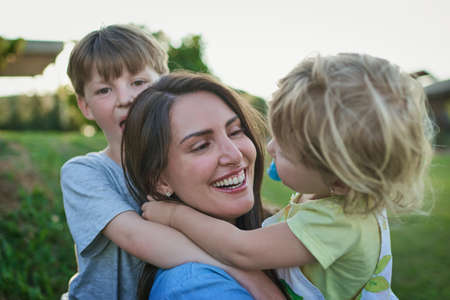 Mommy loves you loads too. a mother bonding with her two little children outdoors.の写真素材