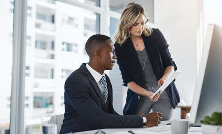 Tapping in to al thatll benefit their business. two businesspeople working together in an office.の写真素材