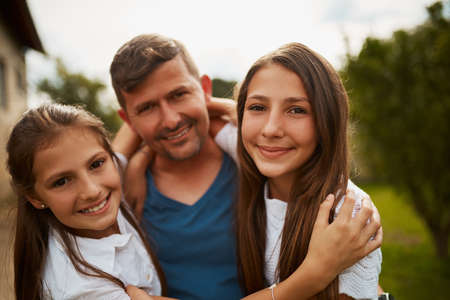 We have the best dad in the world. a handsome man and his two young daughters standing outside.の写真素材
