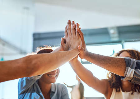 Success will always be ours at the end of the day. a group of businesspeople high fiving together in...