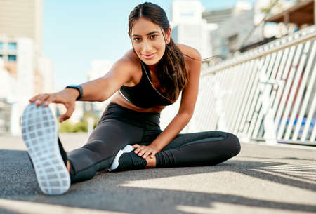 Youll feel yourself getting stronger by the day. Portrait of a sporty young woman stretching before...