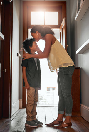 Raising boys is a honor. a woman kissing her son on his forehead.の写真素材