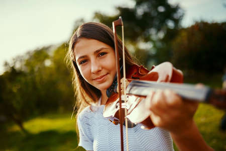 She found her passion at a young age. a young girl playing a violin outdoors.の写真素材