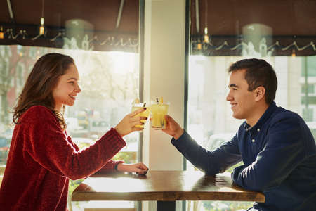 Heres to getting to know each other better. a young man and woman toasting with their drinks on a romantic date at a coffee shop.の写真素材