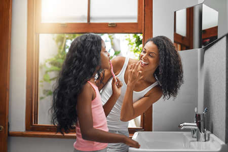 Let me see. an attractive young woman and her daughter brushing their teeth in the bathroom at home.の写真素材