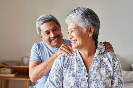 Youre too kind my dear. a cheerful mature woman receiving a massage on her shoulders by her husband at home during the day.の写真素材