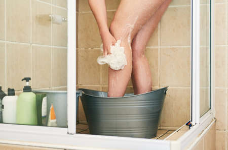 There are simple ways to save water. an unrecognizable woman washing in a bucket that has been placed in the shower at home.の写真素材
