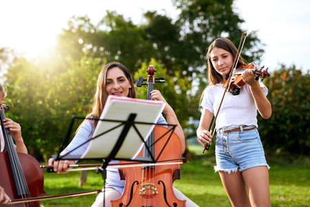 Definitely one of our most favorite pastimes. a young girl playing a violin outdoors.の写真素材