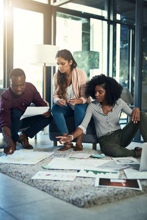 Thats the one Im looking for. a group of young entrepreneurs going through paperwork together in a modern office.の写真素材