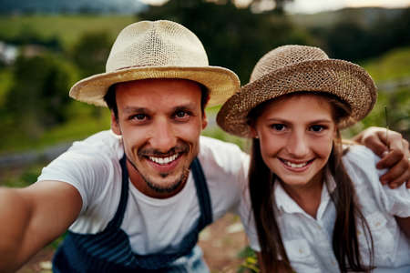 Selfies and sustainable living. Cropped portrait of a handsome man and his young daughter taking selfies while working on their farm.の写真素材
