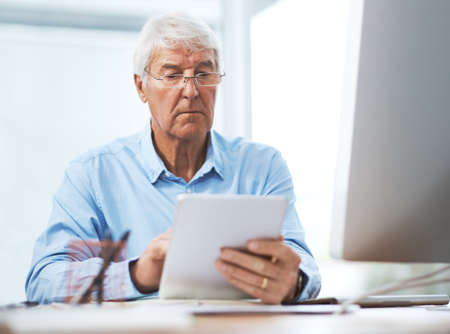 His business is never done. a handsome senior businessman working on a tablet at home.