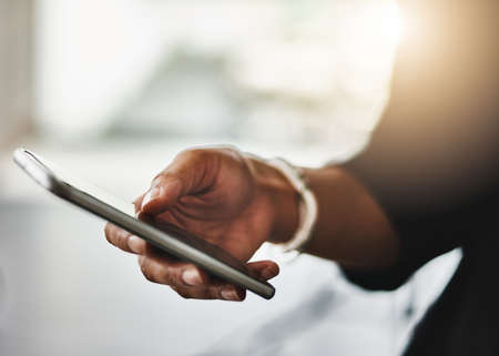 Businesswoman typing on her phone online to reply to an email in the office, close up. Hand of a corporate female in leadership reading an SMS message. Lady executive checking her daily news feedの写真素材