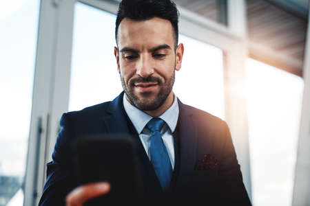 Cellphones are improving the corporate world. a handsome male executive working in a modern office.の写真素材