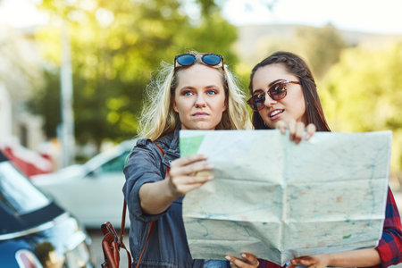 Getting lost is part of the journey. two beautiful female friends looking at a map for directions in the city.の写真素材