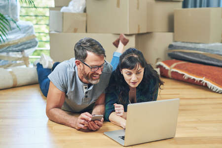 An easy moving day is a planned out one. a husband and wife using a laptop together on moving day.