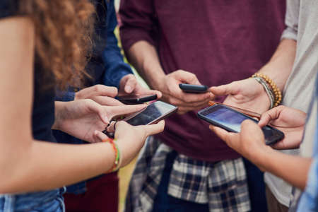Living in a age of technology. a group of young unrecognizable people standing in a circle while...