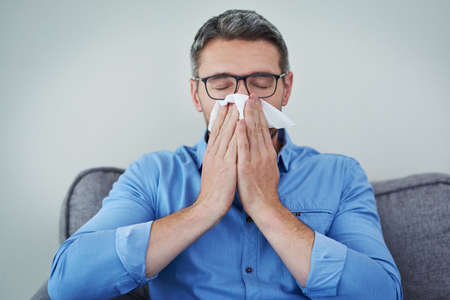 The season of sneezes is here. a mature man blowing his nose.の写真素材