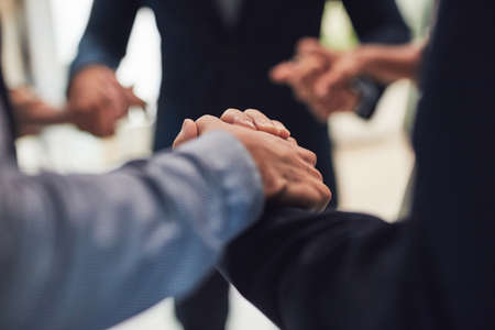 Lets get together and get working. Closeup of a group of unrecognizable businesspeople holding hands...