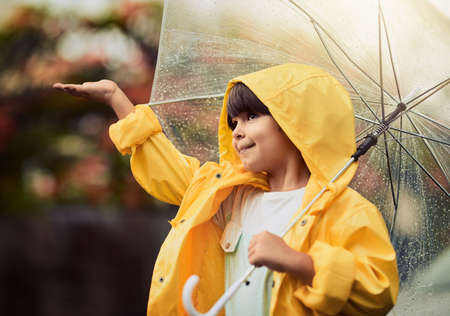 Rainy weather is my favourite type of weather. an adorable little boy in the rain outside.の写真素材