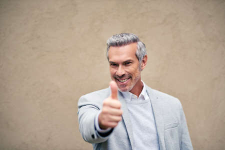 Thumbs up to looking presentable all the time. a smartly dressed mature businessman showing thumbs up outside.の写真素材