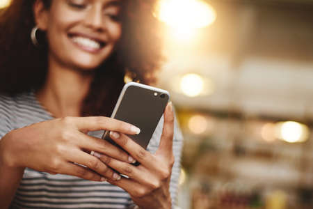 Lets see whats new online. Closeup shot of a young woman using a cellphone in a cafe.